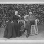 Image: A man and a woman sit outside in wicker chairs