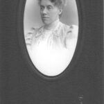 Image: Portrait photograph of a woman facing slightly side on. The photograph itself is an oval shape