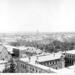 Image: Rooftop view of square courtyard with central tower, with public square in the background