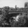 image: pedestrians with parasols cross bridge