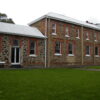 Two storied brick building built in 1880 with lawn