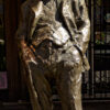 Image: bronze statue of smiling man leaning back with hands in pockets