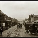 Image: horse drawn carriages on dirt city street