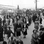 Image: Crowd of people walking passed buildings