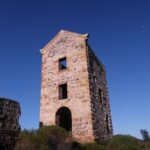 Image: Front view of a tall ruined building surrounded by small bushes