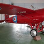 Image: A bright red First World War-era monoplane on static exhibit in a museum