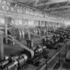 Image: A display of 1880s "electric light machinery" featuring wheels and belts in a large hall.