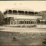 Image: Large two storey house with arches and wrap-around balcony