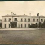 Image: Black and white photograph showing front of large, white two-storey building