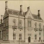 Image: a two storey gothic style building with a central bay window on the second floor above the main entrance, balconets and a steeply pitched roof.