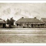 Image: a street-scape of dilapidated single storey cottages with wooden shingle roofs. The verandahs are in particularly poor repair.