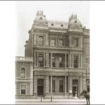 Image: a three storey highly decorative stone building with columns, balconies and a curved mansard roof