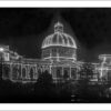 Image: A large building with a domed roof is lit up by hundreds of small globes running along its key architectural features, such as around windows and along roof lines.