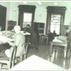 Image: Men sitting at tables reading newspapers in a large room