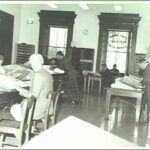 Image: Men sitting at tables reading newspapers in a large room