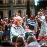 Image: a number of clowns parade past a crowd with a large number of children as part of a Christmas pageant