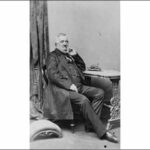 Image: Black and white photograph of seated man in three quarter profile