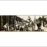 Image: A large group of me pose alongside a partially completed stone building with wooden scaffolding