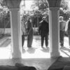 Image: Five Afghan men stand in the courtyard of a building. Two ornate columns are visible in the foreground