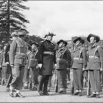 Image: A man in dress uniform walks past a line of soldiers