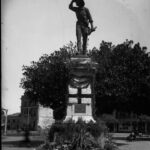 Image: stone statue of man with hand up to shade his eyes while gazing out