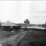 Image: a round kiosk building on the bank of a river.