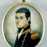 Image: a round miniature watercolour of the head and shoulders of a man with short dark brown hair posed in 3/4 profile wearing a high collared black military style coat with gold epaulettes, piping and buttons over a white shirt