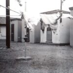 Image: clothesline in front of small, corregated iron buildings.