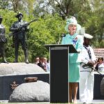 Image: woman at lectern speaking in front of sculpture