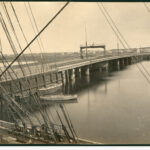 Image: A nineteenth-century swing bridge with centrally located turntable extends across a narrow river. A number of small sailing craft are visible in the river next to the bridge