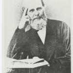 Image: bearded man seated with book