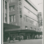 Image: a four storey building with a rounded corner, clad in shiny tiles