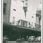 Image: Pedestrians and parked cars in front of a cinema