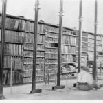 Image: shelves full of documents with person sitting on floor