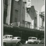 Image: Pedestrians and parked cars in front of a cinema