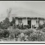 Image: people standing on verandah of small building