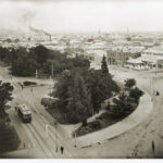 View of a tram and trees in the foreground with cityscape behind