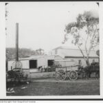 Old stone building with a tall chimney and a horse and cart in the foreground.