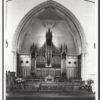 Image: a large church organ under a pointed stone arch