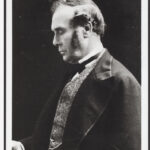 Image: a man poses for a photograph, looking down