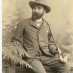 Image: sepia image of seated man wearing hat