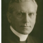 Image: Photographic head-and-shoulders portrait of a middle-aged, clean-shaven Caucasian man in an Anglican reverend's attire