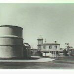 Image: large funnel like building with two story building in background