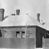 Image: Black and white photograph of the outside of a 19th century villa style building