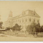 Image: Yellow-toned photograph of a large building with a turret