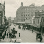 Image: City buildings and sparse horse-drawn traffic in Rundle Street, taken from an elevated position. Dominating the image is a huge five storey hotel building with a cupola on the corner of its roof.