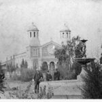 Image: three people standing next to fountain with church in background