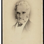 Image: Photographic head-and-shoulders portrait of an elderly Caucasian man in seven eighths view. His grey hair, sideburns and beard are neatly trimmed