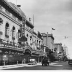 Image: a very ornate theatre building with plants hanging from and on top of its verandah as well as in window boxes on the second storey.