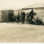 Image: Group of men standing in front of corrugated iron building